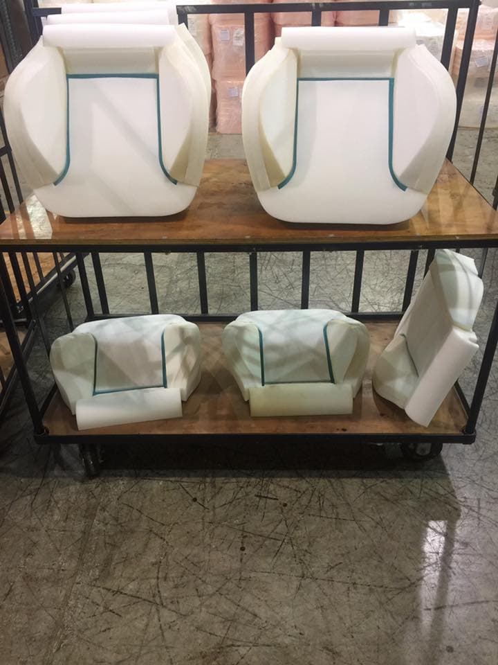 Molded foam seat cushions staged on a fabrication cart